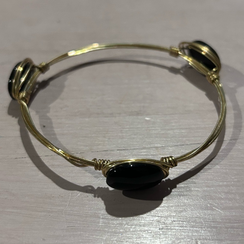 Gold- tone wire-wrapped bangle bracelet with three black onyx beads.
9”